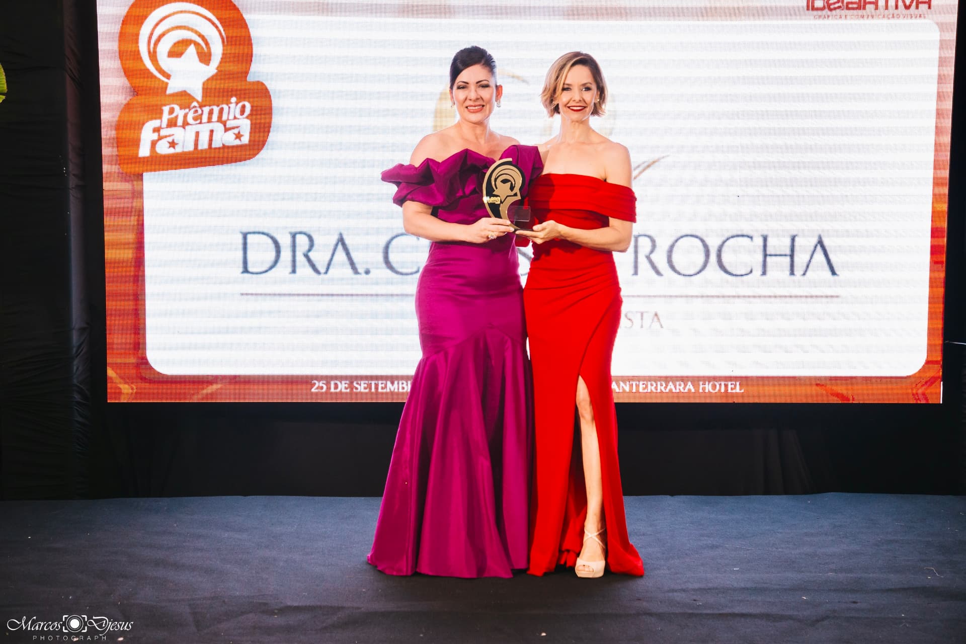 Duas mulheres no palco segurando o troféu dourado do Prêmio Fama